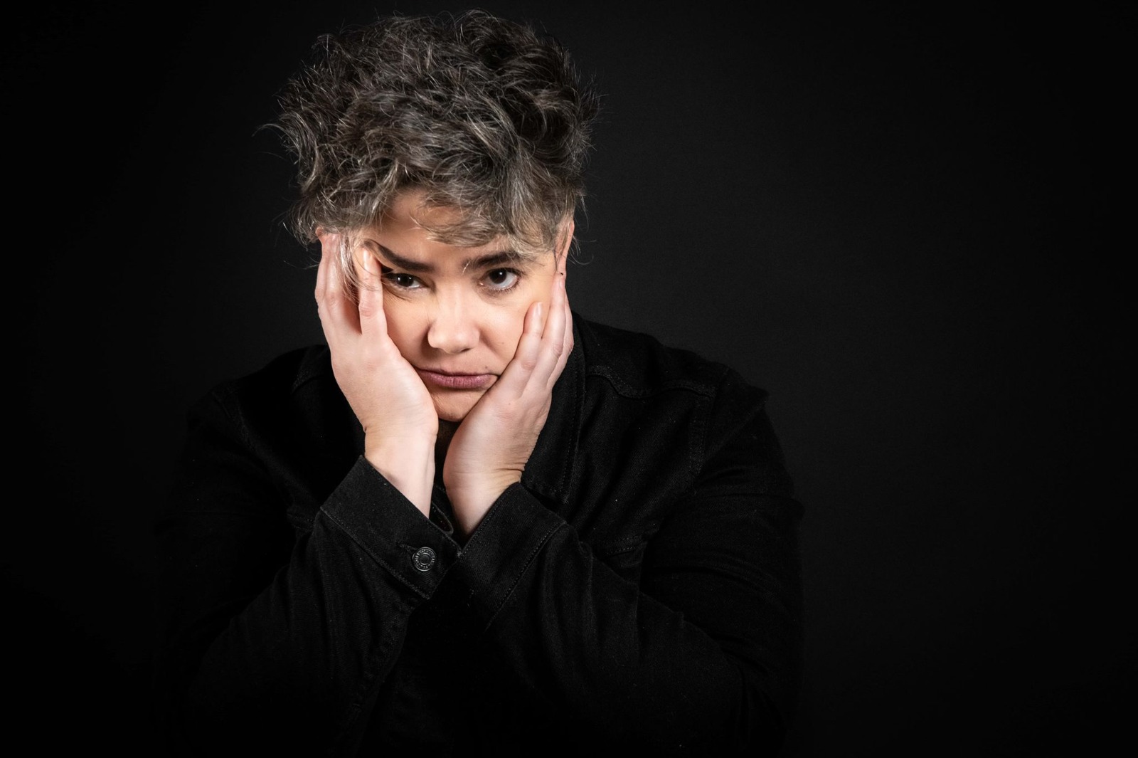 Jimena Márquez sitting in font of a backdrop with her face in her hands.